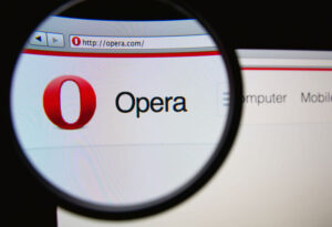 Photo of Opera homepage on a monitor screen through a magnifying glass.