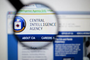 Photo of cia central intelligence agency. page on a monitor screen through a magnifying glass.