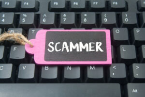 wooden tag written scammer over keyboard button background