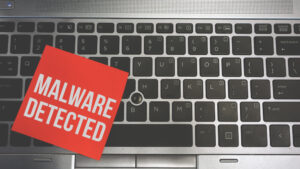 Concept Image of a red sticky note pasted on a keyboard with a message word white in color MALWARE DETECTED