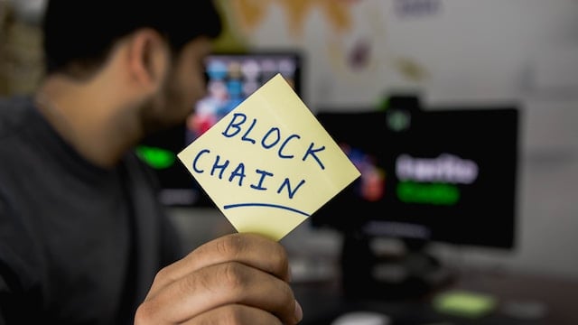 person holding card with blockchain written on it